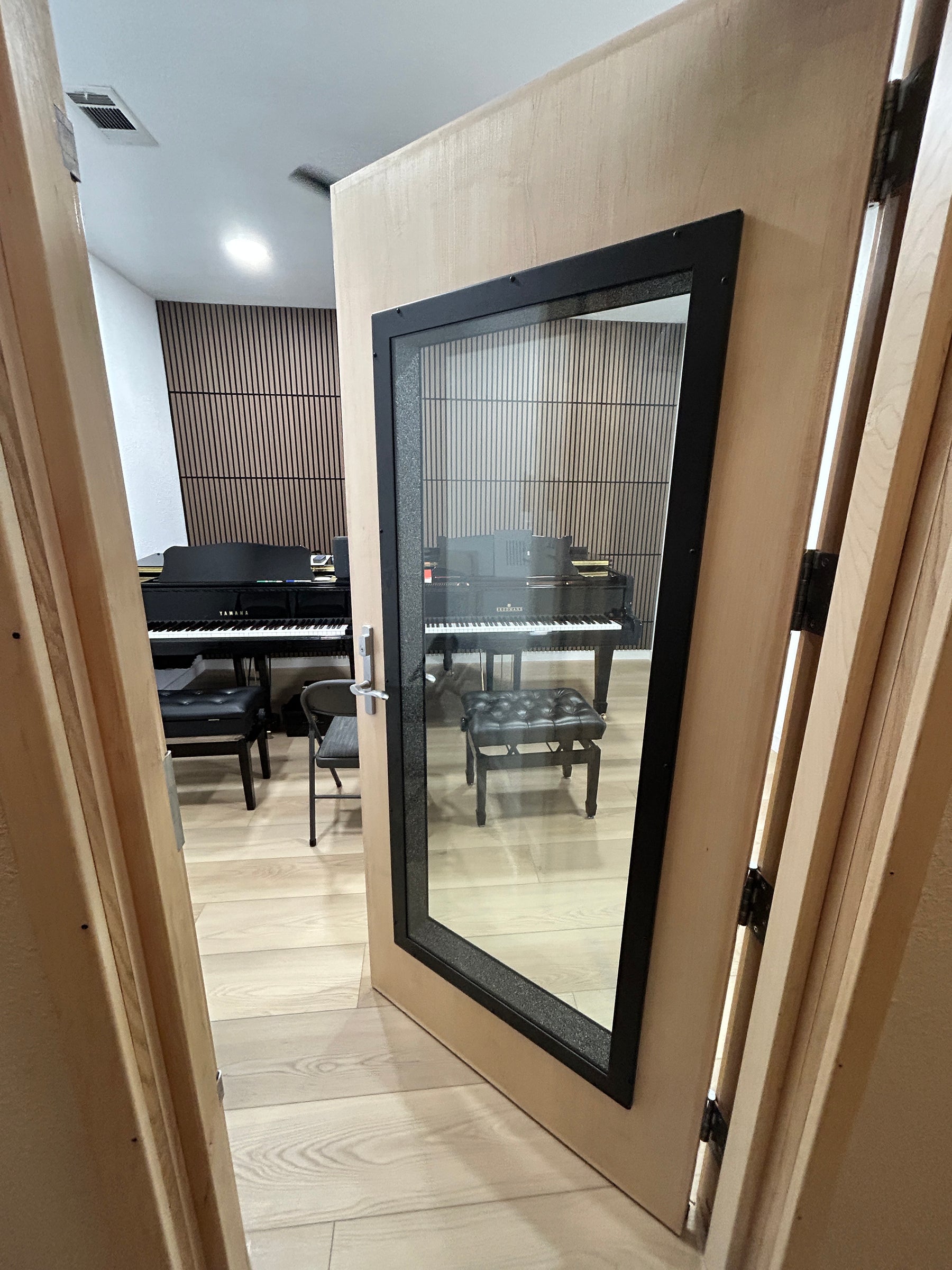 Sound Lock soundproof door with window installed in piano practice room with acoustic wall panels and grand piano