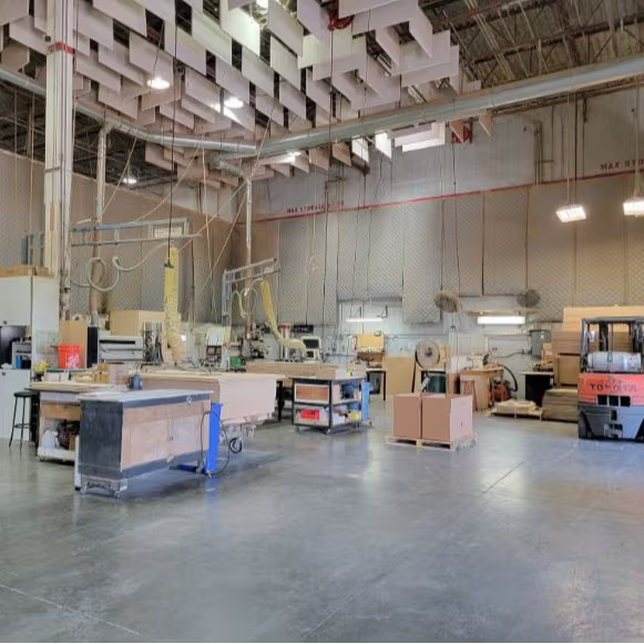 Industrial manufacturing facility interior showing open floor space, machinery, and a Toyota forklift