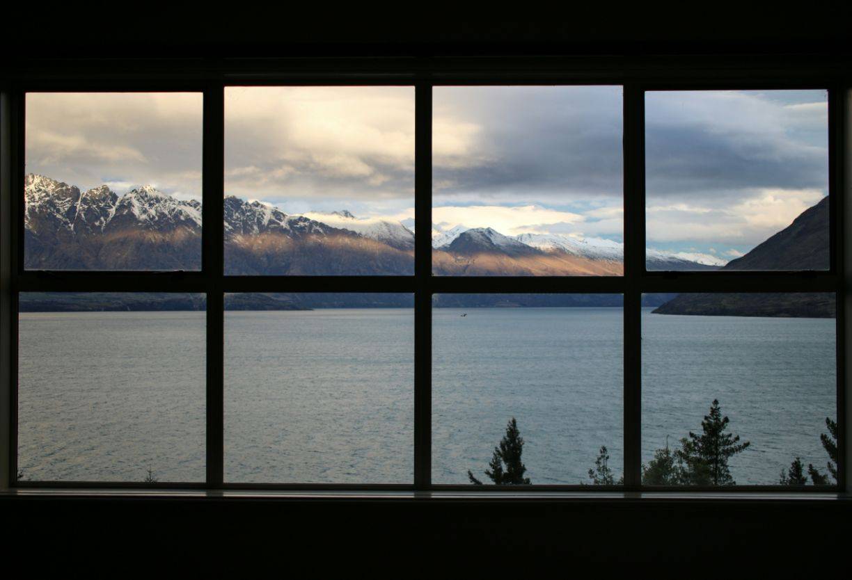 View through large window of snow-capped mountains and lake, illustrating noise and drafts from windows