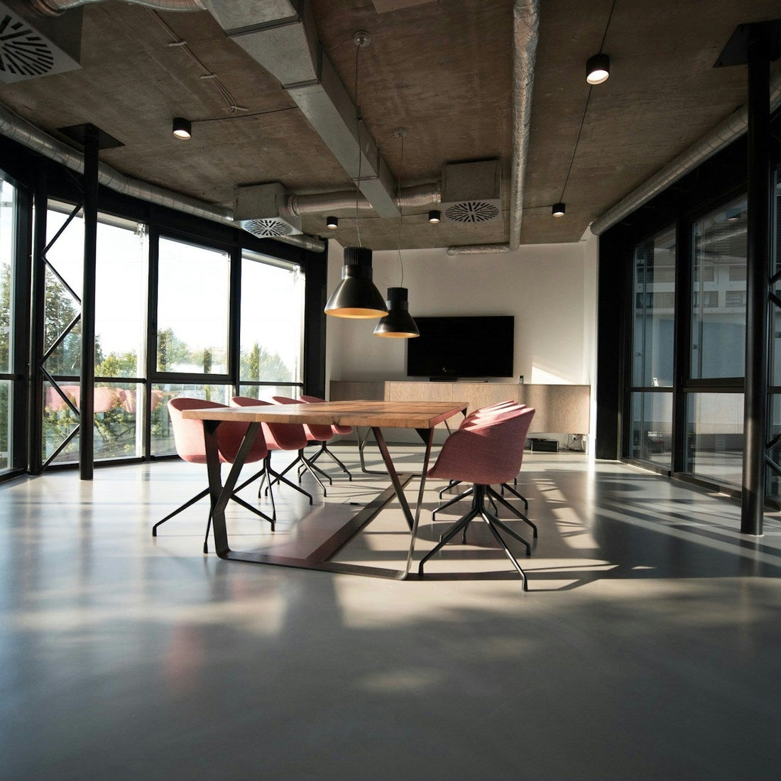 Modern office space with large windows and a long table with chairs.