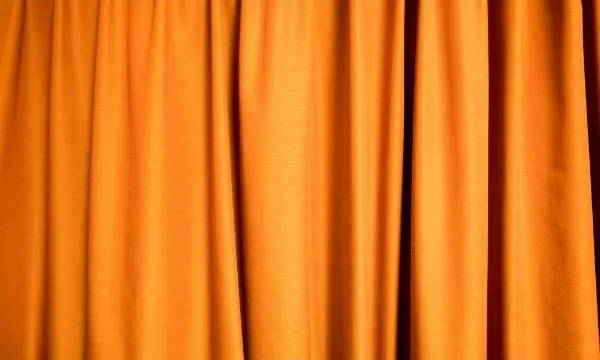 Orange soundproof curtains hanging in vertical folds