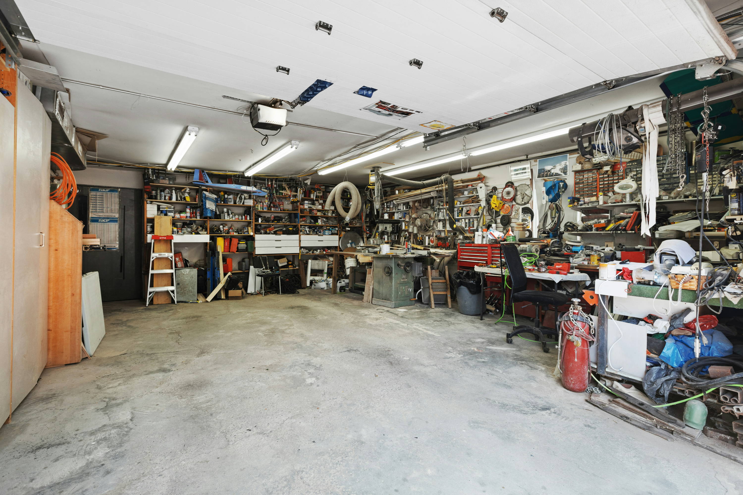 Cluttered garage workshop with tools and shelving, ideal for soundproofing with Second Skin Audio products