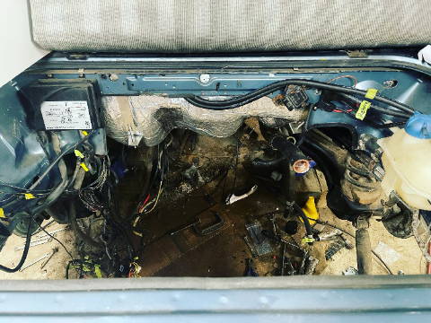 Vehicle firewall area with wiring harness exposed, prepped for sound deadening installation